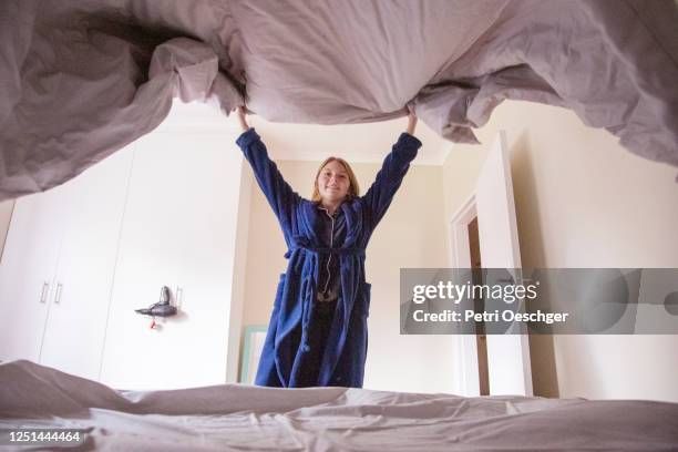 a teenage girl making her bed at home. - tidy room teen stock pictures, royalty-free photos & images