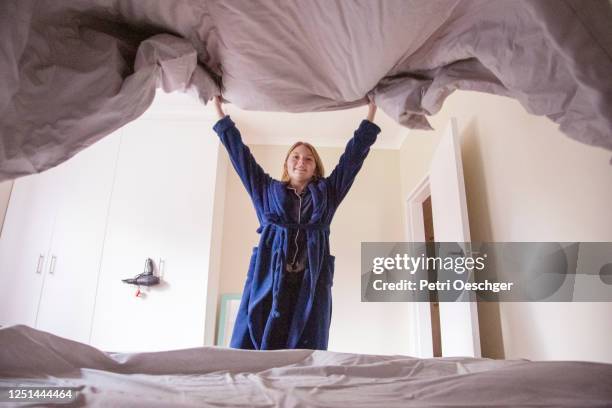 a teenage girl making her bed at home. - tidy bedroom stock pictures, royalty-free photos & images