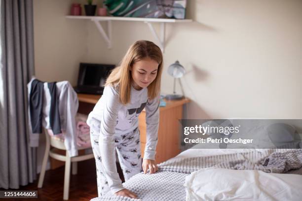 a teenage girl making her bed at home. - sala limpa imagens e fotografias de stock