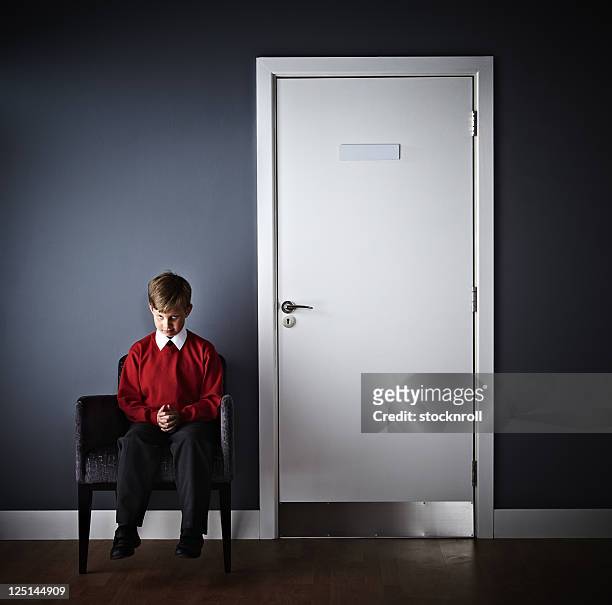 petit garçon assis devant headmaster bureau - school punishment photos et images de collection