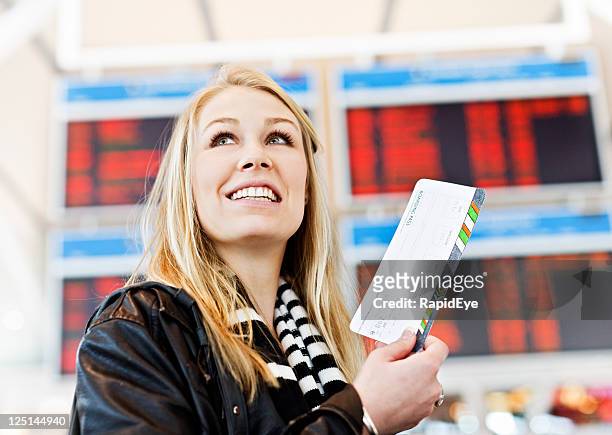 smiling young woman with boarding pass in airport concourse - left eye stock pictures, royalty-free photos & images