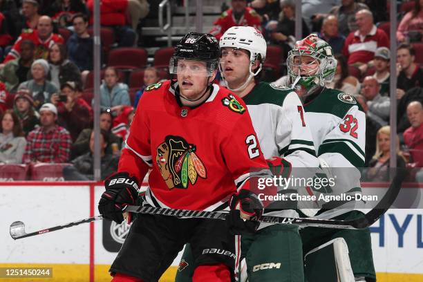 Austin Wagner of the Chicago Blackhawks watches for the puck in front of Brock Faber and goalie Filip Gustavsson of the Minnesota Wild in the third...