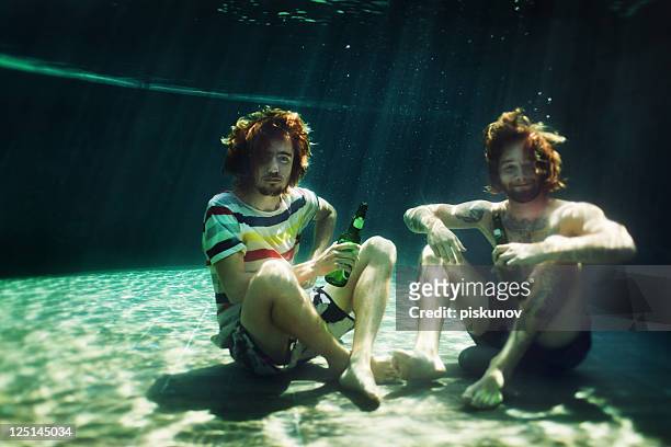 two young men drinking beer in pool - nerd fun stock pictures, royalty-free photos & images
