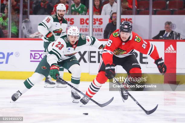Minnesota Wild center Marco Rossi and Chicago Blackhawks left wing Austin Wagner skate after a loose puck during a game between the Minnesota Wild...