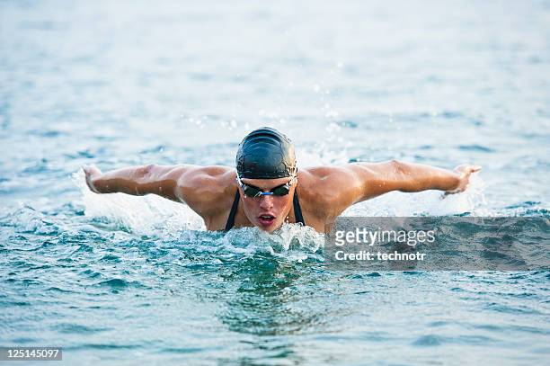 female swimmer at butterfly stroke in the sea - swimming stock pictures, royalty-free photos & images