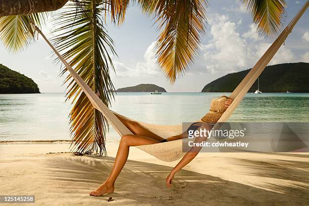 bikini frau schlummern in einer hängematte am strand am karibischen meer - bräune stock-fotos und bilder