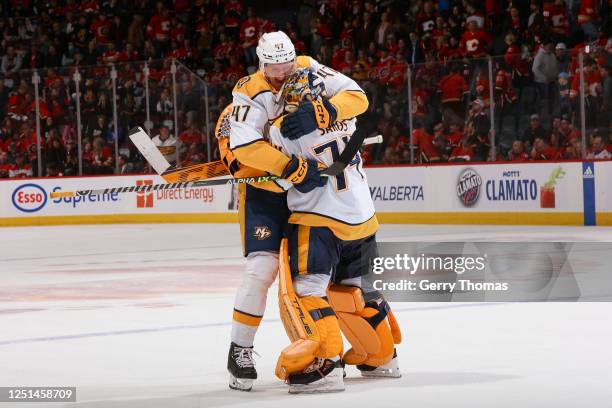 Michael McCarron and Juuse Saros of the Nashville Predators celebrate on ice after a win against the Calgary Flames at Scotiabank Saddledome on April...