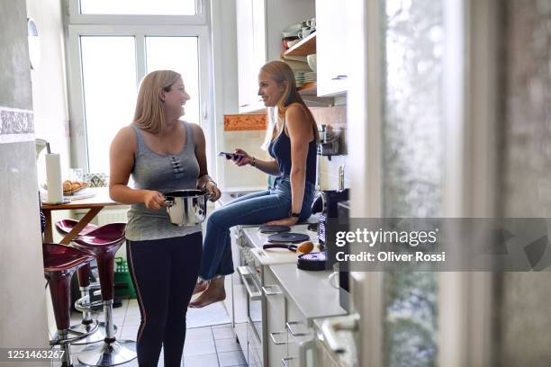 two happy young women in the kitchen at home - roommate stock-fotos und bilder