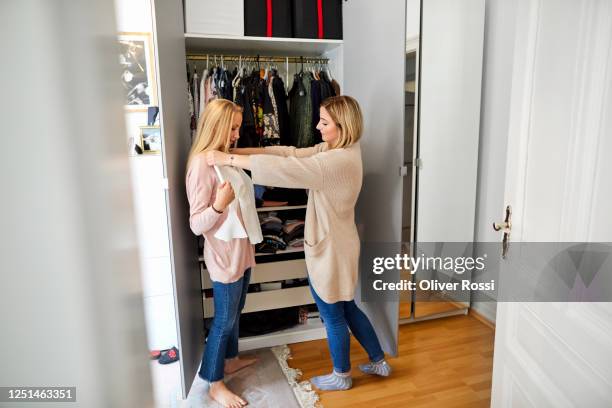 two young women at wardrobe choosing clothes - clothes wardrobe stock-fotos und bilder