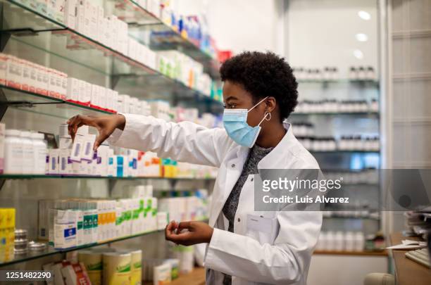 pharmacist wearing face mask working in a pharmacy - schwarzes haar stock-fotos und bilder