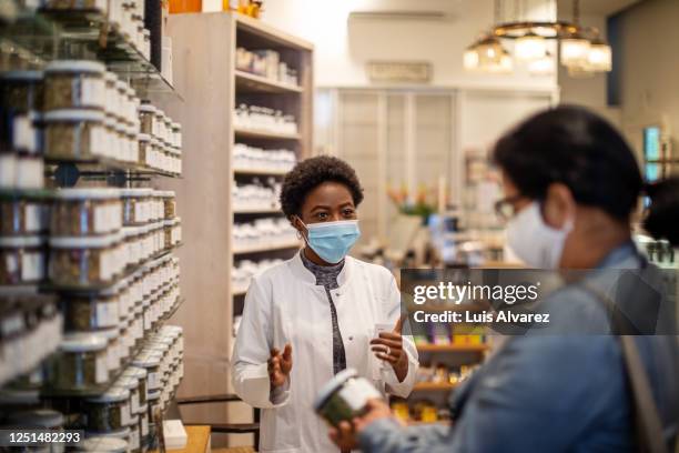 pharmacist explaining medication to female customer - social distancing shopping stock pictures, royalty-free photos & images