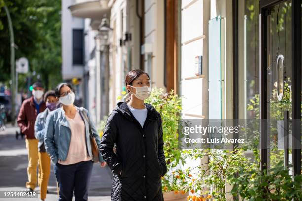 group of people waiting in social distance outside a pharmacy - social distancing stock pictures, royalty-free photos & images
