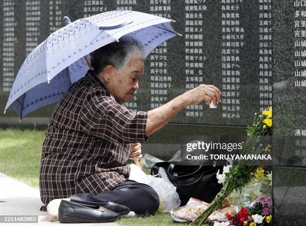 An elderly woman offers a toast to victims before the stone monument on which 230,000 names of civilians and soldiers were killed during the World...