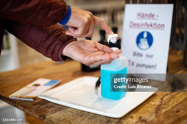 close-up of man cleaning hands with hand sanitizer at pharmacy - change dispenser stock pictures, royalty-free photos & images