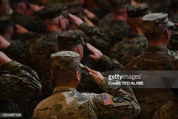 Philippines and US soldiers salute in front of their national flags while their national anthems are played during the opening ceremony of the...