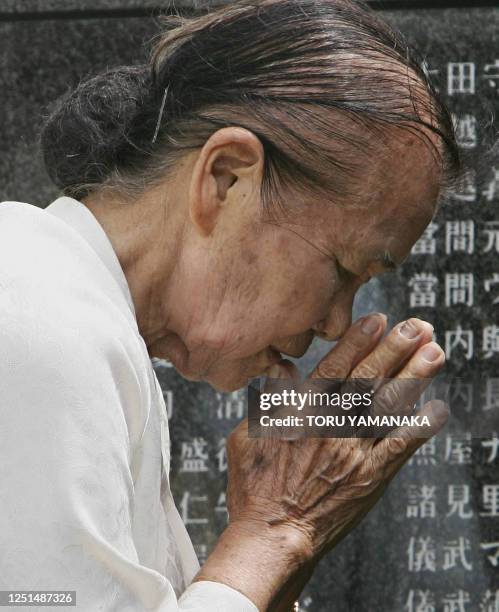 Year-old Haru Yamauchi prays for victims before the stone monument on which 230,000 names of civilians and soldiers were killed during the World War...