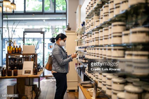 senior woman with face mask buying medicine at drugstore - homeopathie stockfoto's en -beelden