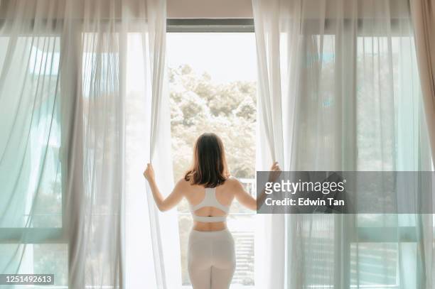 en asiatisk kinesisk vacker kvinna öppna gardin och gå ut på balkongen på morgonen redo att öva yoga - open workouts bildbanksfoton och bilder