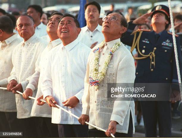 President Fidel Ramos assisted by top government officials looks up as he leads in the raising of the Philippine flag at Rizal park 30 December...