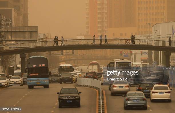 People commute on a street during a sandstorm in Shenyang, in China's northeastern Liaoning province on April 11, 2023. / China OUT