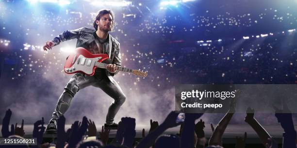 male rock star with red guitar on stage at concert - guitarist stock pictures, royalty-free photos & images