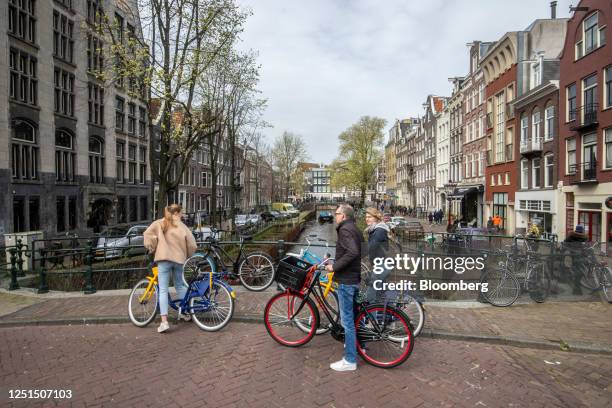 Tourists on rental bikes stop on a bridge over a canal in Amsterdam, Netherlands, on Monday, April 10, 2023. Amsterdam is proposing a wider crackdown...