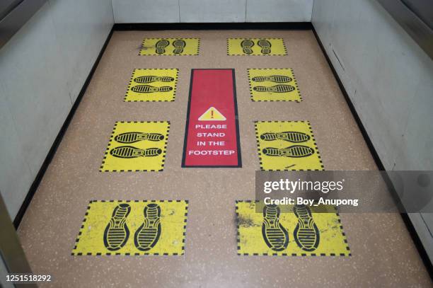 view of yellow footprint sign in lift or elevator for keep space for avoid spreading of virus disease in covid-19 pandemic. - social distancing elevator stock pictures, royalty-free photos & images