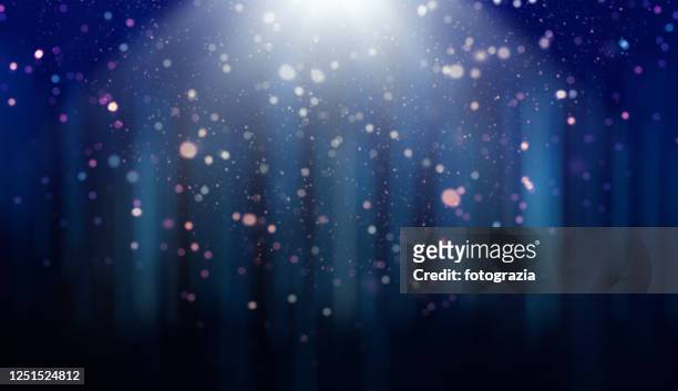 defocused lights, dust particles and light rays over gradient blue background - glamour stock-fotos und bilder