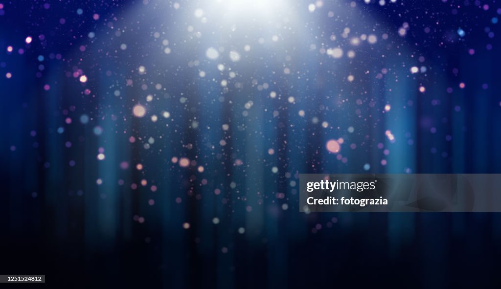 Defocused Lights, Dust Particles and Light Rays over Gradient Blue Background