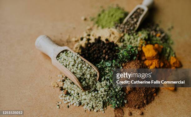 piles of herbs, spices and seasonings on a wooden surface, with scoops - herb stock pictures, royalty-free photos & images