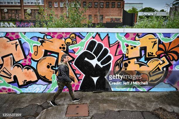 Man walks past a black lives matter mural by artist Boss City Taio on June 23, 2020 in Glasgow, Scotland. Black Lives Matter protests are continuing...
