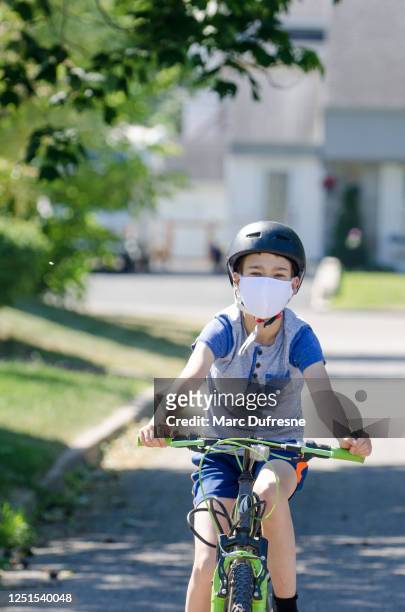 boy on bike with fabric face mask and helmet - cloth mask stock pictures, royalty-free photos & images