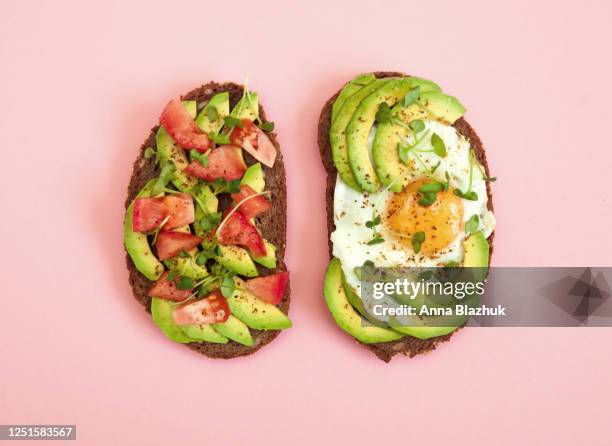 toasts of dark bread with avocado slices, red tomatoes, fried egg and microgreen. top view with pink background. - avocado salad stock pictures, royalty-free photos & images