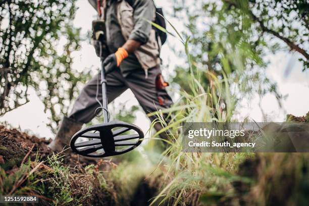 mens die naar schatten zoekt die in de grond met de metaaldetector worden begraven - schatzoeken stockfoto's en -beelden