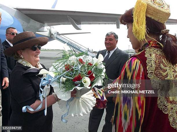 Secretary of State Madeleine Albright smiles as she receives flowers from a girl dressed in traditional Uzbek costume at an airport in Samarkand 17...