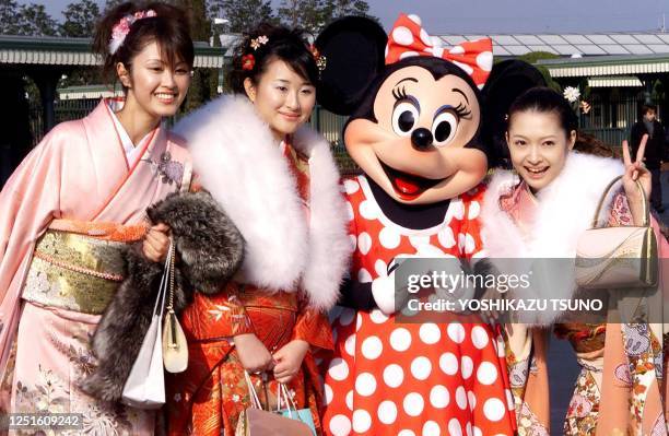 Young Japanese women aged 20 in traditional kimono dresses Mariko Nakayama, Tomomi Akazawa and Yuka Kataoka pose with Minnie Mouse for their souvenir...