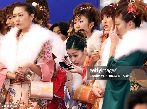 Female attendant , among young Japanese women aged 20 in kimono dresses, touches up her make-up during the ceremony to celebrate Coming-of-Age Day at...