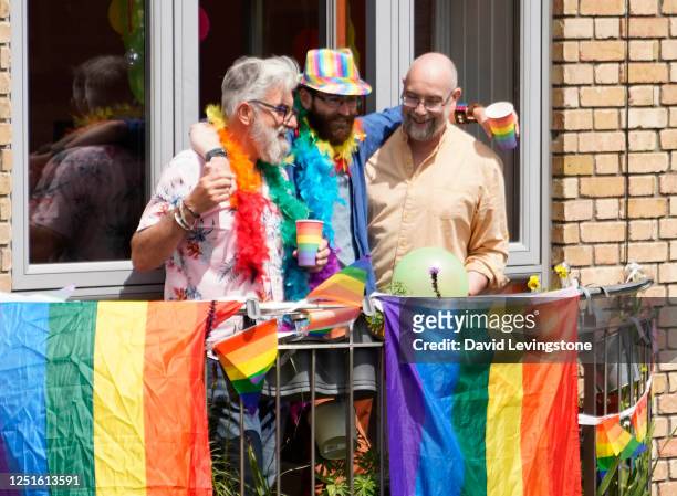 a group of friends celebrating gay pride on their balcony in support of lgbtqi+ pride at home. - ポリアモリー ストックフォトと画像