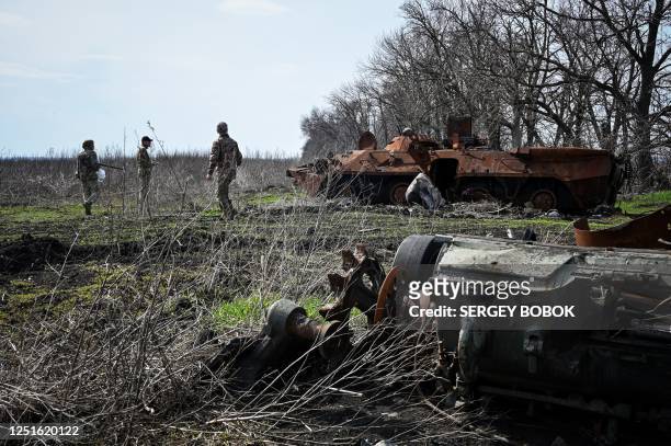 Ukrainian servicemen inspect remains of destroyed armored vehicles at former position of Russian troops in the north of Kharkiv region on April 11...