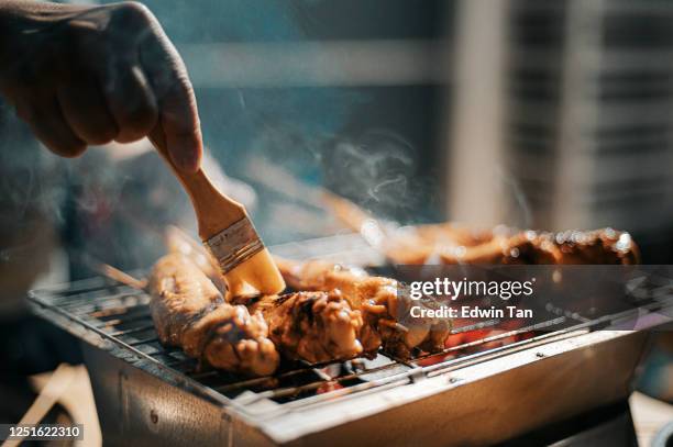 eine nacht bbq party-treffen mit lebensmittelzubereitung bürsten und auftragen von öl und honig auf hühnerflügel - chicken wing stock-fotos und bilder