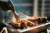a night bbq party gathering with food preparation brushing and applying oil and honey on chicken wing