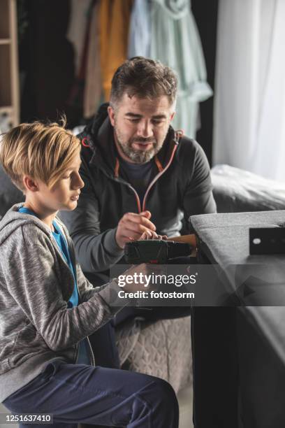 father and son building together a sofa during quarantine times - lockdown drill stock pictures, royalty-free photos & images