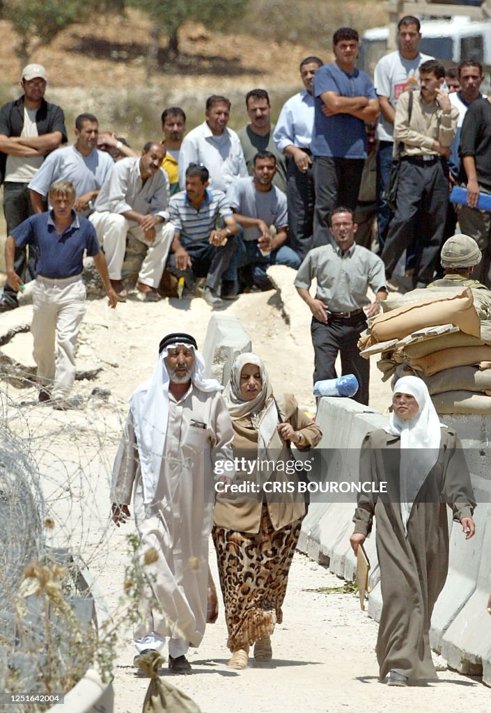 Palestinian women and an older man walk through the Surda checkpoint ...