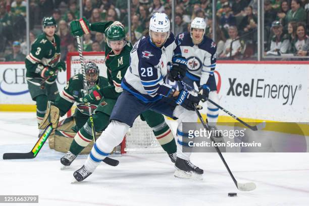 Winnipeg Jets center Kevin Stenlund skates with the puck while being defended by Minnesota Wild defenseman Jon Merrill during the NHL game between...