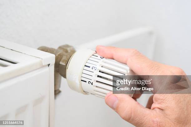 man's hand adjusting the temperature of a radiator. - electric heater fotografías e imágenes de stock