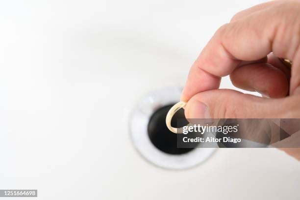 man holding gold wedding ring just below the sink drain. are you going to get rid of it? - obesvarad kärlek bildbanksfoton och bilder