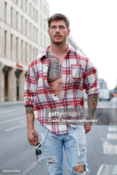 Influencer, model and actor Angelo Carlucci, wearing light blue acid wash, ripped and distressed denim jeans by Levis, a white and red checkered...