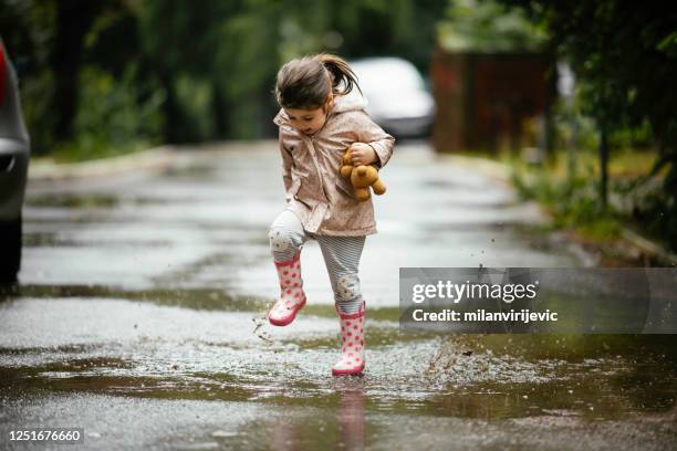 gelukkig meisje dat op de foto van de regenvoorraad springt - standing in the rain girl stockfoto's en -beelden