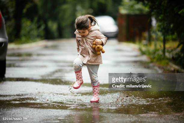 happy little girl jumping on the rain stock photo - stamping feet stock pictures, royalty-free photos & images