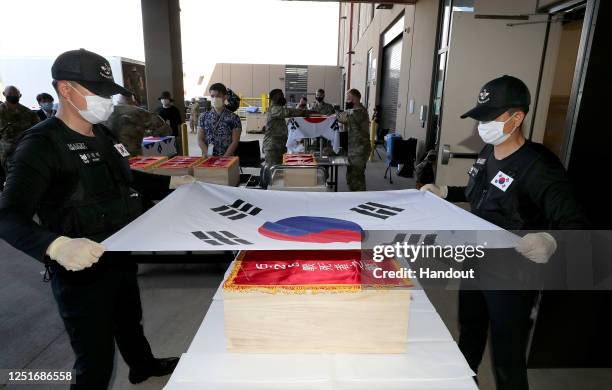 In this handout image taken on June 23, 2020 and provided by South Korean Defense Ministry, South Korean soldiers wrapping a coffin containing the...